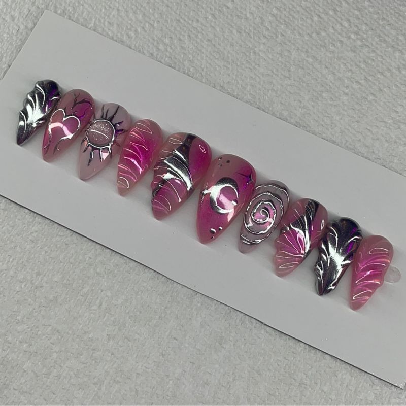 Obsidian Orchid set — almond press-ons in magenta jelly tones with hand-drawn chrome swirls, hearts and a sun motif.